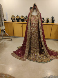 Traditional embroidered outfit with a red dupatta on a mannequin against a neutral background.