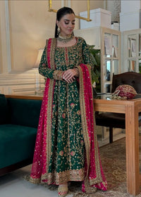 Woman in a traditional green and pink embroidered outfit in an indoor setting.Haris Shakeel Formal