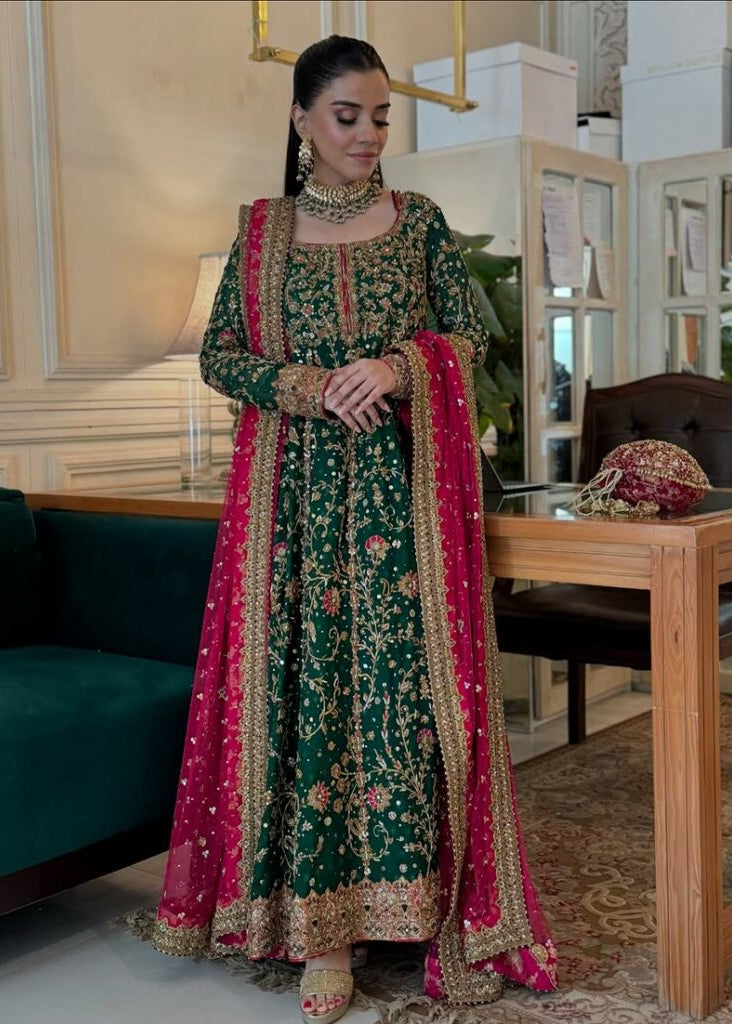 Woman in a traditional green and pink embroidered outfit in an indoor setting.Haris Shakeel Formal